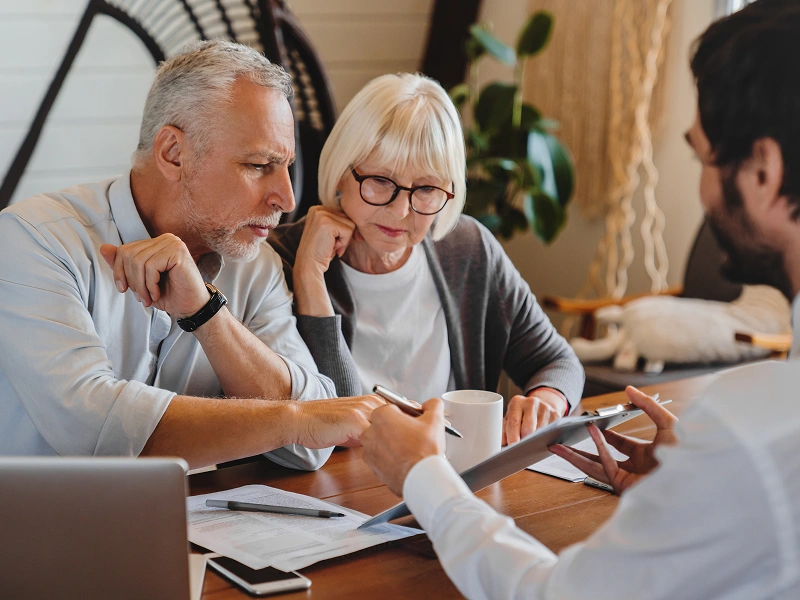 Elderly couple consulting with financial advisor.