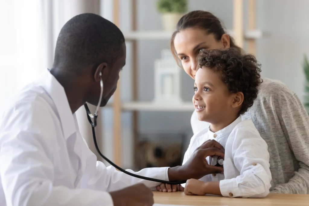 Doctor examining smiling child with stethoscope.