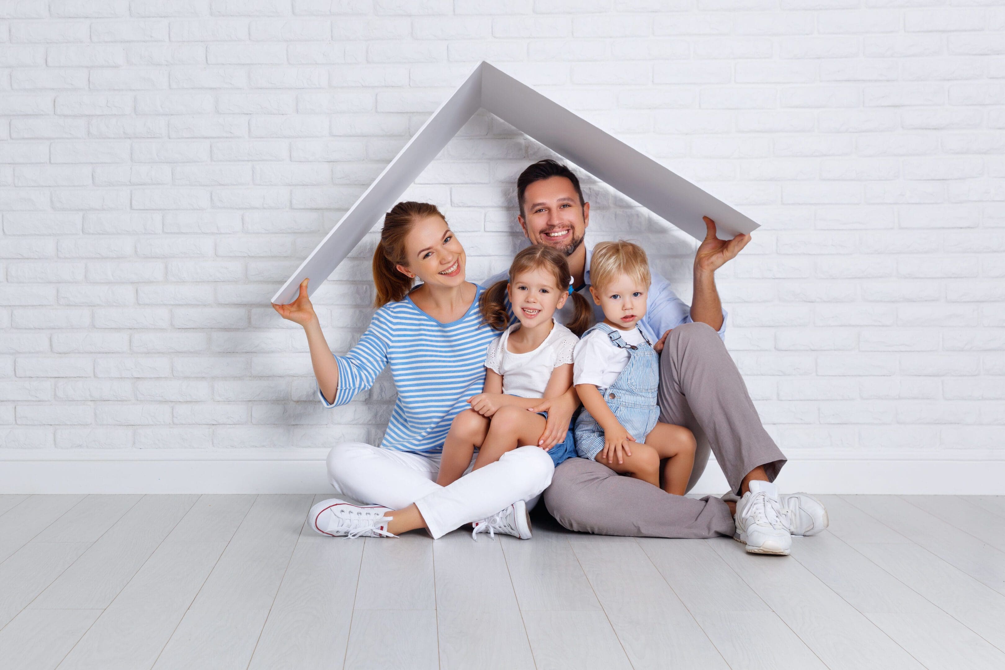 Happy family with two children sitting under a house-shaped frame.