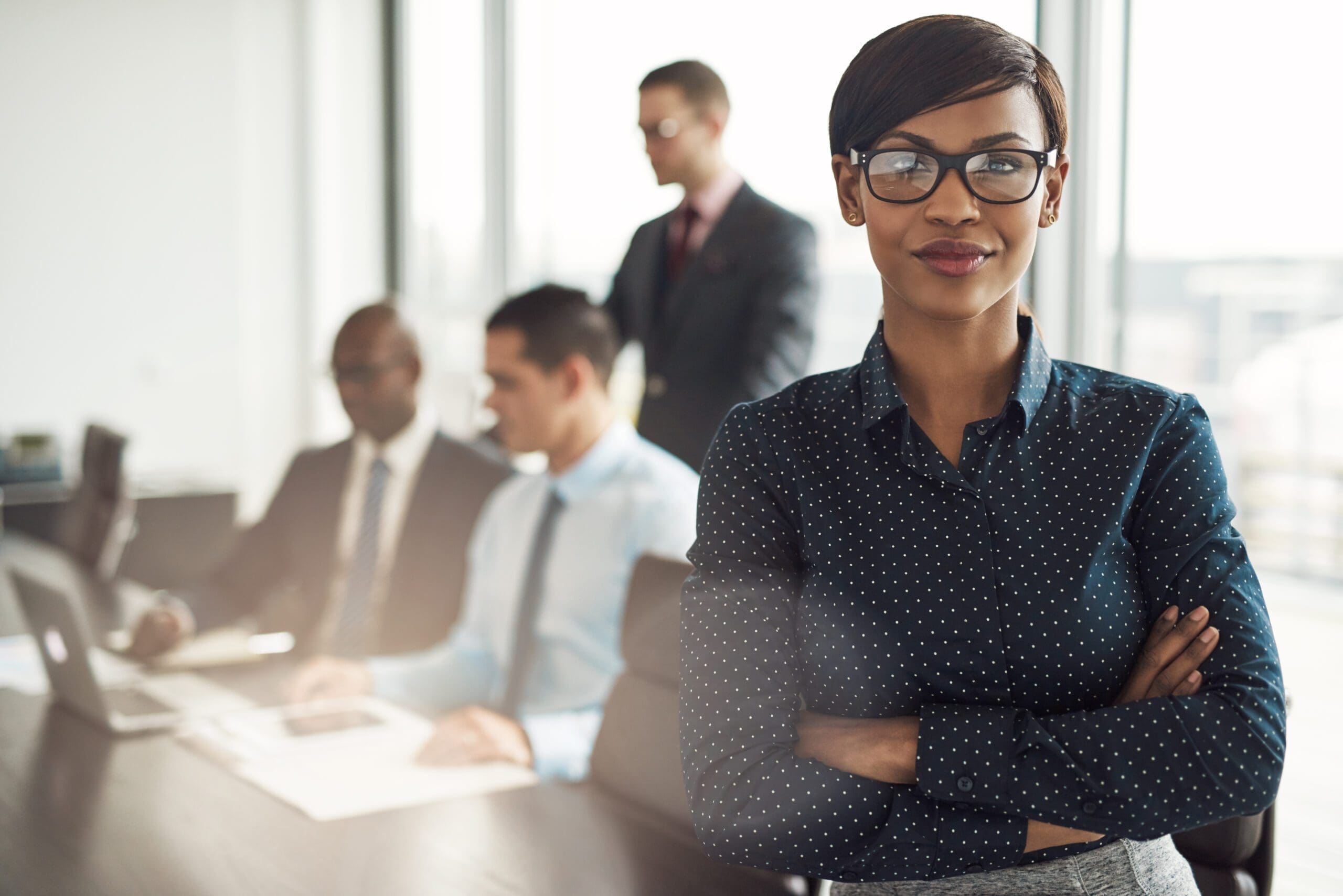 Confident businesswoman with colleagues in a meeting room.
