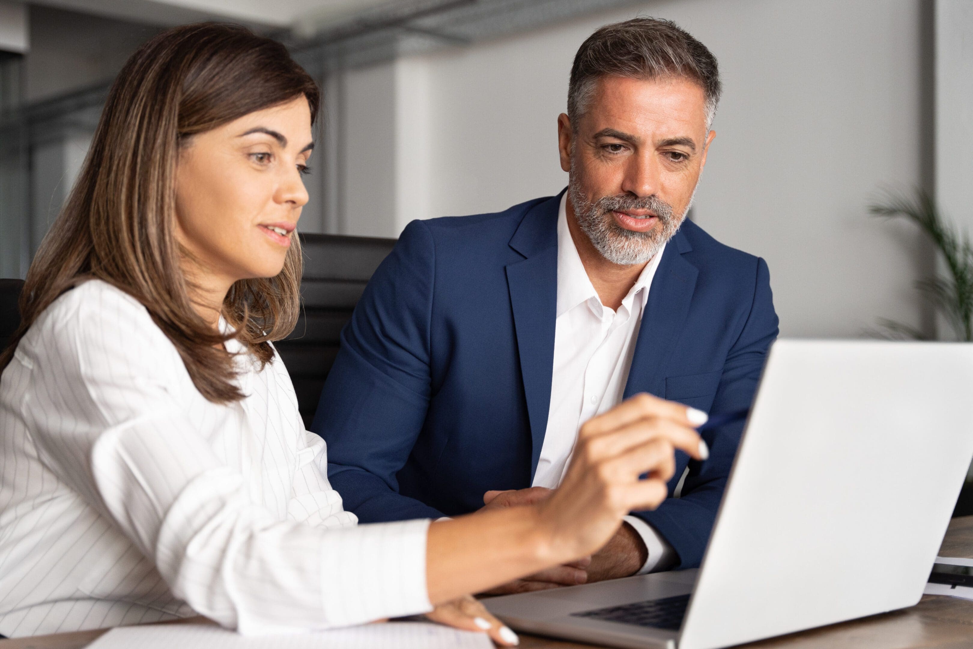 Two professionals reviewing information on a laptop.